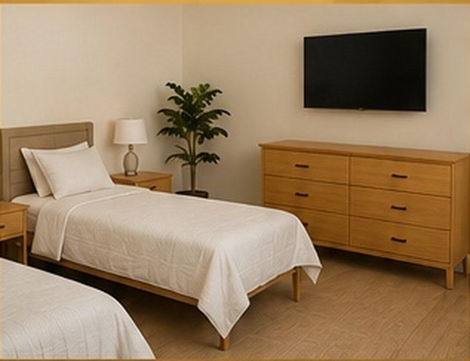 A furnished bedroom with a made bed, dresser, and wall-mounted television